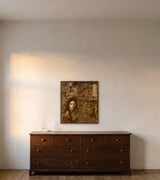 Release from Sorrow by Frantisek Strouhal: a woman's face above sepia columns and a figure with a raised arm, the 28 by 28 inch print in a dark oak floater frame, hanging above a low chest of drawers in a calm room, shown at its true size