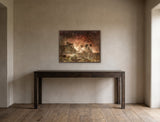 The Bathers by Frantisek Strouhal: draped figures at the water's edge below a ruined castle in dark red haze, the 32 by 24 inch print in a dark oak floater frame, hanging above a dark oak console table in a calm room, shown at its true size
