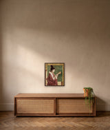 Abundance by Frantisek Strouhal: woman in a red patterned kimono holding a shell, green panel and ochre border, the 16 by 20 inch print in a dark oak floater frame, hanging above a walnut cabinet in a calm room, shown at its true size