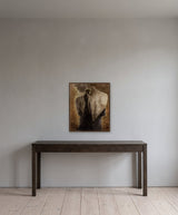 Innocence by Frantisek Strouhal: woman in profile framed by large blurred bare backs, ochre and grey, the 24 by 30 inch print in a dark oak floater frame, hanging above a dark oak console table in a calm room, shown at its true size