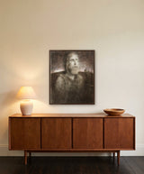 Celestial Sound by Frantisek Strouhal: a bearded man looking upward in dark olive and brown light, the 24 by 30 inch print in a dark oak floater frame, hanging above a walnut sideboard in a calm room, shown at its true size