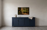 Sunshine Coast by Frantisek Strouhal: a wooden footbridge over a shallow creek in a mossy old growth forest, the 33 by 22 inch print in a black painted floater frame, hanging above a navy painted cupboard in a calm room, shown at its true size