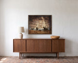 Horse Riding on the Beach by Frantisek Strouhal: three horses and riders at the surf line under a rust sky, the 30 by 24 inch print in a dark oak floater frame, hanging above a walnut sideboard in a calm room, shown at its true size