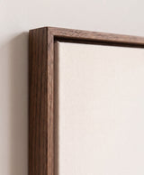 The corner of the dark oak floater frame, with the shadow gap that runs all the way round between the canvas and the wood.