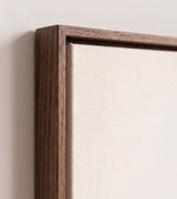 The corner of the dark oak floater frame, with the shadow gap that runs all the way round between the canvas and the wood.