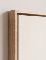 The corner of the pale oak floater frame, with the shadow gap that runs all the way round between the canvas and the wood.