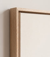 The corner of the pale oak floater frame, with the shadow gap that runs all the way round between the canvas and the wood.