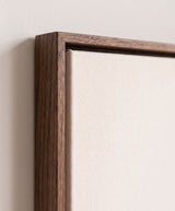 The corner of the dark oak floater frame, with the shadow gap that runs all the way round between the canvas and the wood.