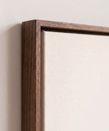The corner of the dark oak floater frame, with the shadow gap that runs all the way round between the canvas and the wood.
