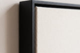The corner of the black painted floater frame, with the shadow gap that runs all the way round between the canvas and the wood.