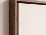 The corner of the dark oak floater frame, with the shadow gap that runs all the way round between the canvas and the wood.