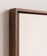 The corner of the dark oak floater frame, with the shadow gap that runs all the way round between the canvas and the wood.