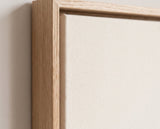 The corner of the pale oak floater frame, with the shadow gap that runs all the way round between the canvas and the wood.