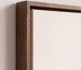 The corner of the dark oak floater frame, with the shadow gap that runs all the way round between the canvas and the wood.