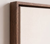 The corner of the dark oak floater frame, with the shadow gap that runs all the way round between the canvas and the wood.