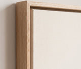 The corner of the pale oak floater frame, with the shadow gap that runs all the way round between the canvas and the wood.