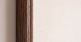 The corner of the dark oak floater frame, with the shadow gap that runs all the way round between the canvas and the wood.