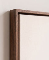 The corner of the dark oak floater frame, with the shadow gap that runs all the way round between the canvas and the wood.