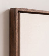 The corner of the dark oak floater frame, with the shadow gap that runs all the way round between the canvas and the wood.