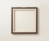 The back of the framed canvas: the canvas stretched over light wooden bars and stapled around the inner edge, one sawtooth hanger fitted to the top bar, and no bracing across the middle. The frame edge is dark oak.