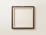 The back of the framed canvas: the canvas stretched over light wooden bars and stapled around the inner edge, one sawtooth hanger fitted to the top bar, and no bracing across the middle. The frame edge is dark oak.