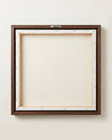 The back of the framed canvas: the canvas stretched over light wooden bars and stapled around the inner edge, one sawtooth hanger fitted to the top bar, and no bracing across the middle. The frame edge is dark oak.