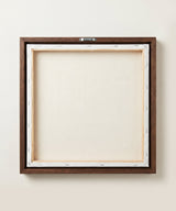The back of the framed canvas: the canvas stretched over light wooden bars and stapled around the inner edge, one sawtooth hanger fitted to the top bar, and no bracing across the middle. The frame edge is dark oak.