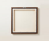 The back of the framed canvas: the canvas stretched over light wooden bars and stapled around the inner edge, one sawtooth hanger fitted to the top bar, and no bracing across the middle. The frame edge is dark oak.