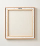 The back of the framed canvas: the canvas stretched over light wooden bars and stapled around the inner edge, one sawtooth hanger fitted to the top bar, and no bracing across the middle. The frame edge is pale oak.
