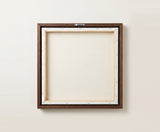 The back of the framed canvas: the canvas stretched over light wooden bars and stapled around the inner edge, one sawtooth hanger fitted to the top bar, and no bracing across the middle. The frame edge is dark oak.