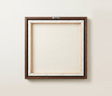 The back of the framed canvas: the canvas stretched over light wooden bars and stapled around the inner edge, one sawtooth hanger fitted to the top bar, and no bracing across the middle. The frame edge is dark oak.