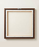 The back of the framed canvas: the canvas stretched over light wooden bars and stapled around the inner edge, one sawtooth hanger fitted to the top bar, and no bracing across the middle. The frame edge is dark oak.