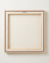 The back of the framed canvas: the canvas stretched over light wooden bars and stapled around the inner edge, one sawtooth hanger fitted to the top bar, and no bracing across the middle. The frame edge is pale oak.