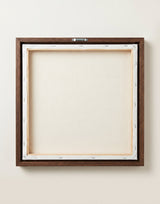 The back of the framed canvas: the canvas stretched over light wooden bars and stapled around the inner edge, one sawtooth hanger fitted to the top bar, and no bracing across the middle. The frame edge is dark oak.