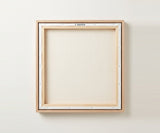 The back of the framed canvas: the canvas stretched over light wooden bars and stapled around the inner edge, one sawtooth hanger fitted to the top bar, and no bracing across the middle. The frame edge is pale oak.