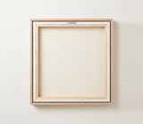 The back of the framed canvas: the canvas stretched over light wooden bars and stapled around the inner edge, one sawtooth hanger fitted to the top bar, and no bracing across the middle. The frame edge is pale oak.