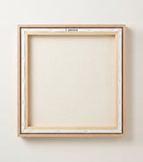 The back of the framed canvas: the canvas stretched over light wooden bars and stapled around the inner edge, one sawtooth hanger fitted to the top bar, and no bracing across the middle. The frame edge is pale oak.