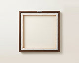 The back of the framed canvas: the canvas stretched over light wooden bars and stapled around the inner edge, one sawtooth hanger fitted to the top bar, and no bracing across the middle. The frame edge is dark oak.