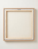The back of the framed canvas: the canvas stretched over light wooden bars and stapled around the inner edge, one sawtooth hanger fitted to the top bar, and no bracing across the middle. The frame edge is pale oak.